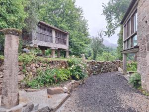 a stone wall next to a house with a porch at Casa de mestre 2 in Freijo