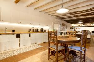 a kitchen with a wooden table and some chairs at Masia del siglo xvi in Vallbona