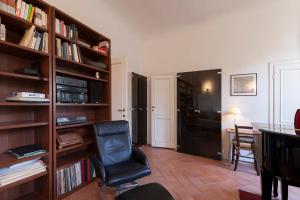 ein Wohnzimmer mit einem Stuhl und einem Bücherregal in der Unterkunft Grand Piano Apartment in Florenz