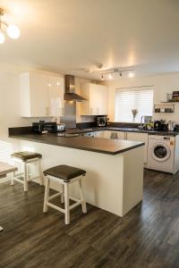 a large kitchen with a counter and chairs in it at Spacious and Modern 4BR with Hot Tub and Garden in Peterborough