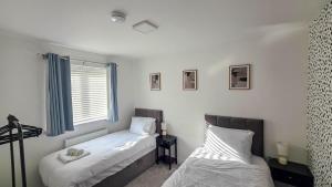a bedroom with two beds and a window at Spacious and Modern 4BR with Hot Tub and Garden in Peterborough