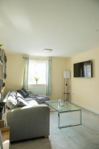 a living room with a couch and a glass table at Spacious and Modern 4BR with Hot Tub and Garden in Peterborough