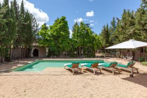 a swimming pool with chairs and an umbrella at Masia del siglo xvi in Vallbona