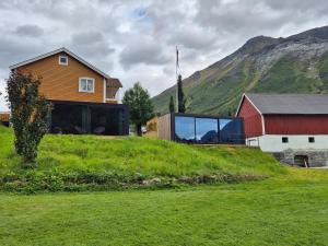 a glass house on a hill with a red barn at Hytte Blåtind, Rekkedal Gjestegard - Sæbø in Sæbø