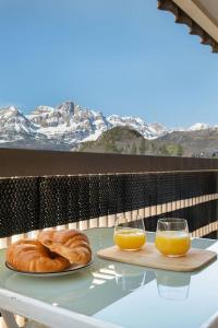 a table with two plates of bread and two glasses of orange juice at Relax en Pirineo l Vistas l Wifi l Balcón in Panticosa