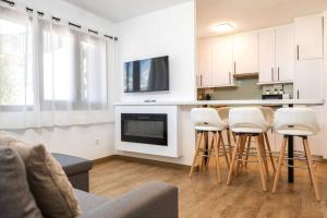 a living room with a kitchen with a bar and stools at Relax en Pirineo l Vistas l Wifi l Balcón in Panticosa +12 photos