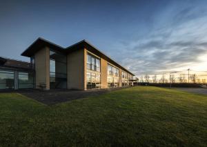 a building with a grass field in front of it at Jetsmark Idrætscenter in Pandrup