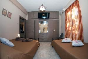 a hotel room with two beds and a television at Seaside Plitra Paradiso - Steps from the Beach in Plytra