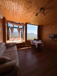 a living room with a couch and a large window at Villa Kapreshumi in Itʼkhvisi