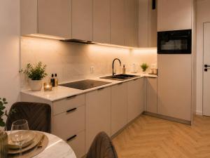 a kitchen with white cabinets and a sink and a table at Ceglana Apart 01A in Katowice