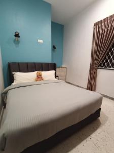 a bed with a teddy bear sitting on top of it at Austin Homestay in Ipoh