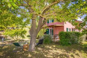 a table and chairs under a tree in front of a house at Piccolo Paradiso - Riparbella in Riparbella