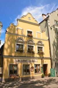 un bâtiment jaune avec des boîtes de fleurs sur son côté dans l'établissement Restaurant-Café-Pension Himmel, à Landshut
