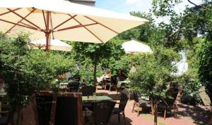 a patio with an umbrella and people sitting at tables at Restaurant-Café-Pension Himmel in Landshut