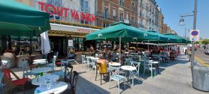 an outdoor cafe with tables and chairs and umbrellas at Dieppe plage à 2min à pied in Dieppe