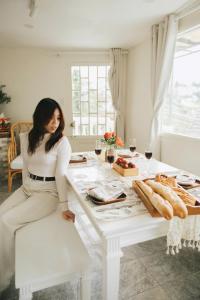a woman sitting on a white chair at a table with food at StayDalat in Ấp Ða Lợi