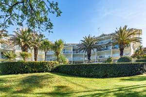 a large building with palm trees in front of it at Entre Foret et Ocean in Moliets-et-Maa