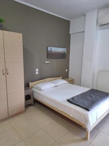 a bedroom with a large bed and a cabinet at Achilleas Apartments in Paralía Skotínis
