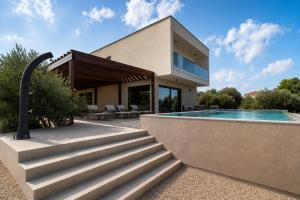 a villa with a swimming pool and a house at Courtside Luxury Villa Dalmatia in Dobropoljana