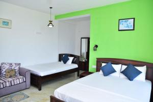 a room with two beds and a couch and green walls at Hill Forest Cottage in Ella