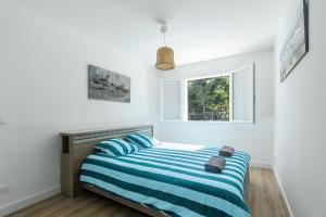 a bedroom with a bed with blue and white stripes at Villa Bourdaines - Conciergerieland in Vielle-Saint-Girons +14 photos