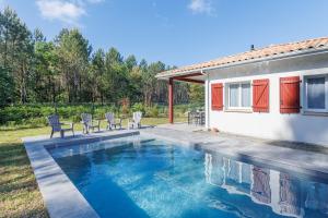 a swimming pool with chairs and a house at Villa Bourdaines - Conciergerieland in Vielle-Saint-Girons