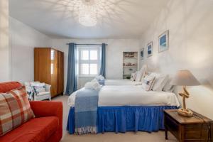 a bedroom with two beds and a red couch at Driftwood - Pittenweem in Pittenweem