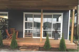 a house with a porch with a sliding glass door at The Weiti Waterfront in Whangaparaoa