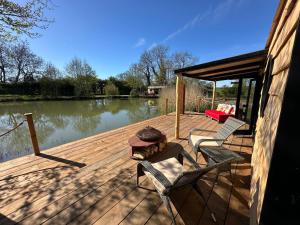 a woman sitting on a wooden deck next to a lake at Scranton luxury fishing pod with private fishing Jetty in Spilsby