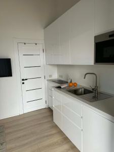 a kitchen with white cabinets and a sink at Navi Jūra House13 in Palanga