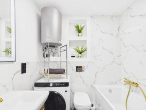 a white bathroom with a sink and a washing machine at Apartamenty Retro Loft in Chorzów