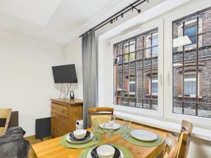 a dining room with a table and two windows at Apartamenty Retro Loft in Chorzów
