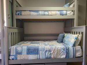 a bedroom with a bunk bed with blue and white sheets at Eden Dunes 75B in Shelly Beach