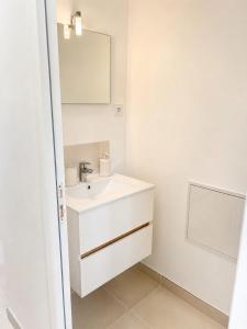 a white bathroom with a sink and a mirror at Petit Castel in Châteaubriant