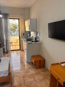 a living room with a kitchen with a stove and a tv at Aleka Apartments in Kos