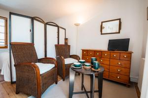a living room with chairs and a table and a tv at Gîte L'inattendue in Courseulles-sur-Mer