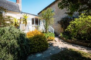 a house with a balcony and bushes in front of it at Gîte L'inattendue in Courseulles-sur-Mer