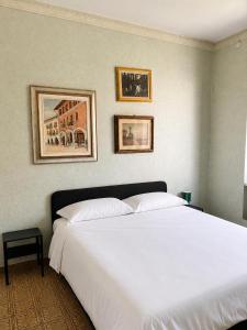 a white bed in a bedroom with two pictures on the wall at Giuditta Apartment in Ciriè