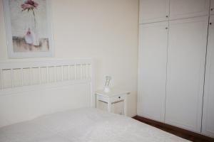 a white bedroom with a bed and a cabinet at Brandungsbad 36 in Grömitz +6 photos