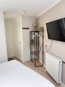 a bedroom with a bed and a flat screen tv at Bed & Beach Zeekraal in De Koog