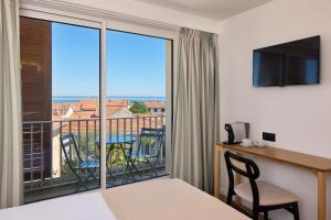 a room with a bed and a balcony with a view at Best Western Arcachon Le Port in Arcachon