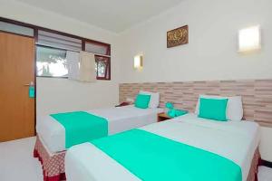 two beds in a room with green and white at Hotel Lestari Near Lippo Plaza Mall Jember in Jember