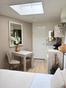 a room with a table and a kitchen with a window at Bed & Beach Zeekraal in De Koog