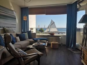 a living room with a couch and a sail boat in the window at Strandhotel Wohnung 16 in Dahme