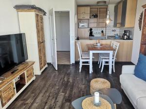 a living room with a television and a table with chairs at Strandhotel Wohnung 16 in Dahme +8 photos
