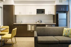 a living room with a couch and a kitchen at Quest East Perth in Perth