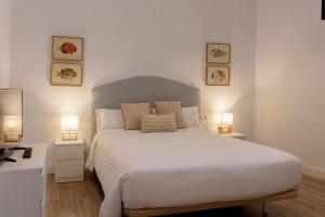 a bedroom with a large white bed with two lamps at Apartamentos El Patio Plaza de Santa Clara - con vistas en el casco histórico in Cáceres