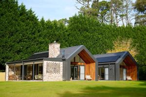 a house on a lawn with trees in the background at The Vale Penrose in Penrose