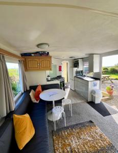 a caravan living room with a blue couch and a table at Carn Kenidjack View Caravan, space, peace and tranquillity in Penzance