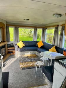 a living room with a blue couch and a table at Carn Kenidjack View Caravan, space, peace and tranquillity in Penzance
